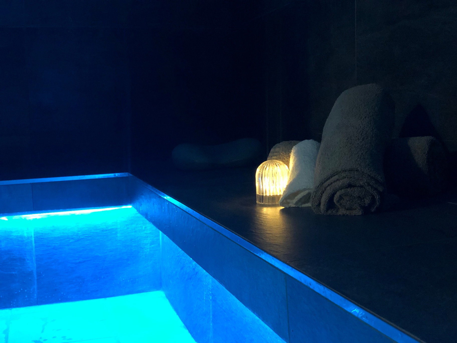 Bassin illuminé et serviettes roulées à la lueur d'une bougie